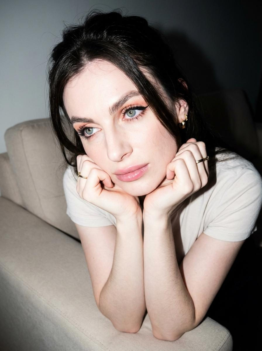 Thoughtful Woman Sofa Pose Pastel Eyeshadow Close Up – The woman in the uploaded reference image (DO NOT TOUCH FACE) sit