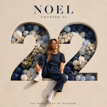 A person in denim overalls sitting inside a large numeral 22 made of navy, royal blue, white, and silver balloons against a beige wall.
