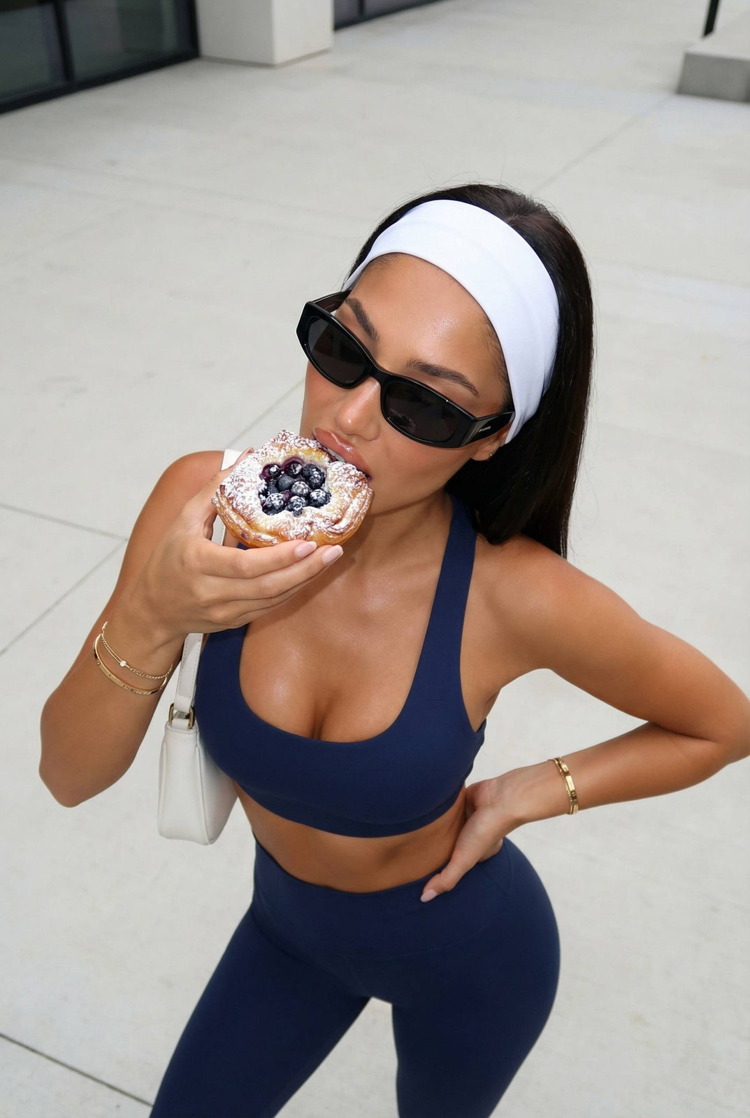 Woman in navy sports bra holding a berry pastry, high-angle shot.