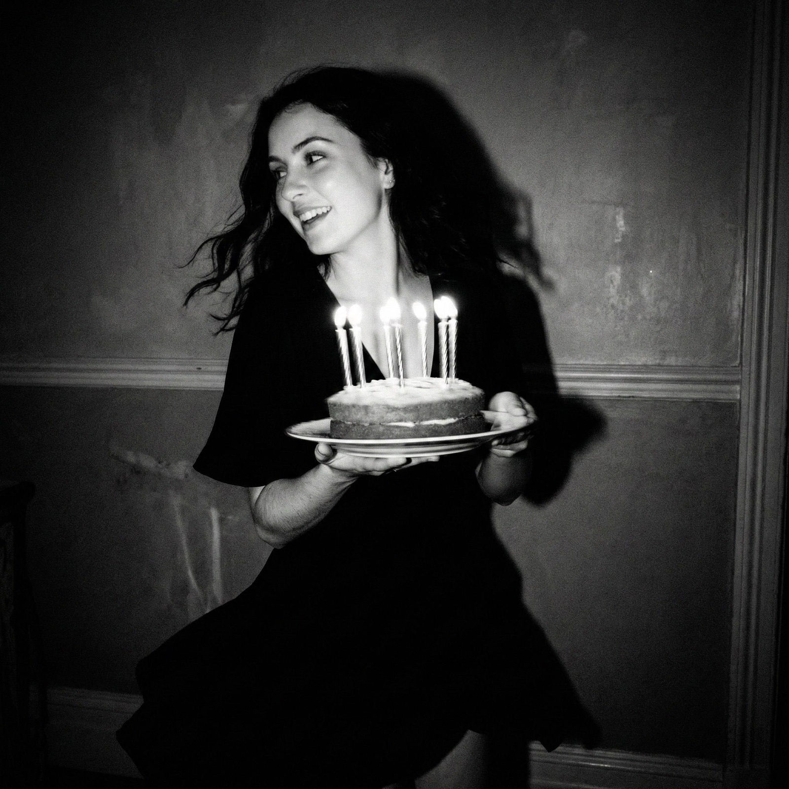 A young woman in a flowing dress, mid-motion, holding a birthday cake with lit candles, under a softly glowing candlelight.