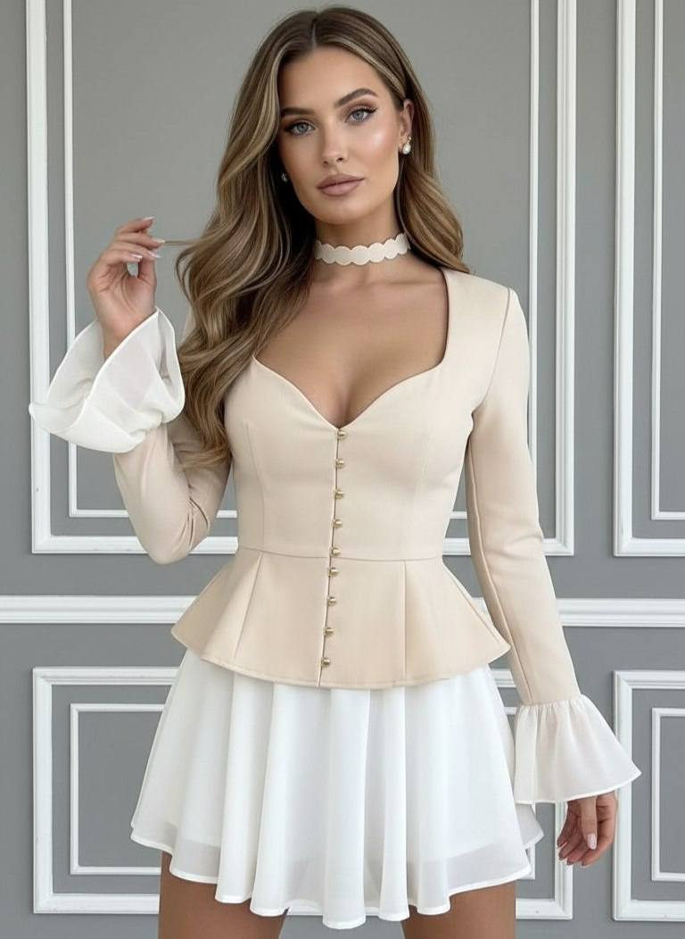 Confident half-body fashion portrait against a classic grey wall, wearing a structured cream-beige peplum top and flared chiffon skirt.
