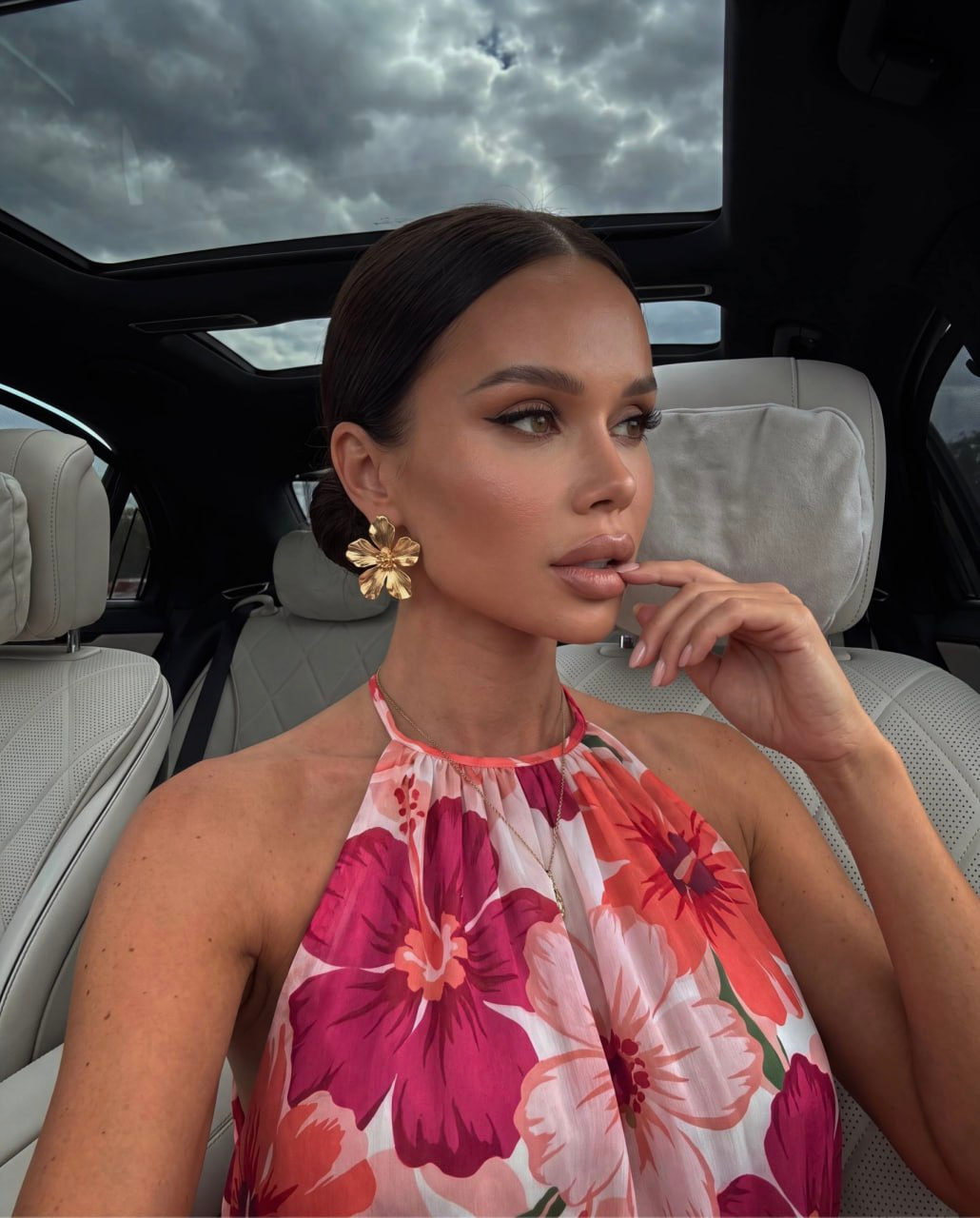 Close-up portrait of a woman in a luxury car, touching her lips elegantly.