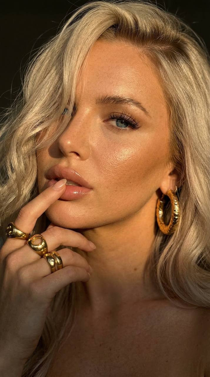 Close up of a model showcasing golden jewelry under soft side light, highlighting her luminous skin and elegant features.