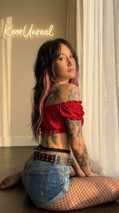 A radiant woman in an arched back pose, dressed in a red crop top and denim shorts, caught in golden hour light.