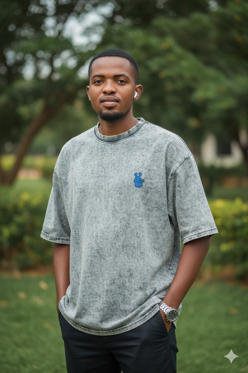 Ultra-realistic portrait of a man in a stylish oversized light gray T-shirt with a calm expression against a blurred outdoor background.
